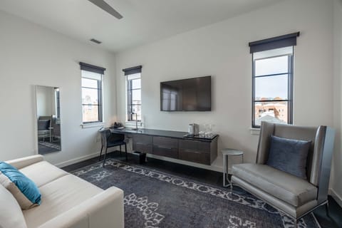 Suite style room features a desk, TV, kitchenette, and couch seating area.