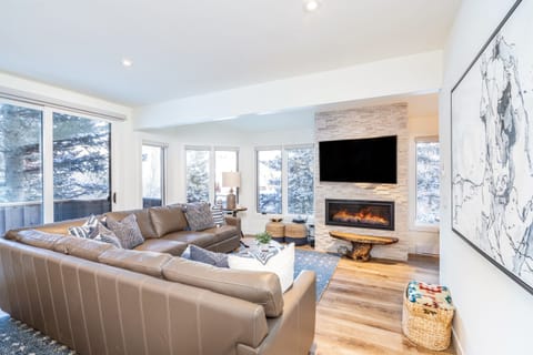 Bright and spacious living room with a large sectional, TV, and fireplace.