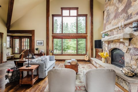 Stunning living area with a stone fireplace and floor to ceiling views.