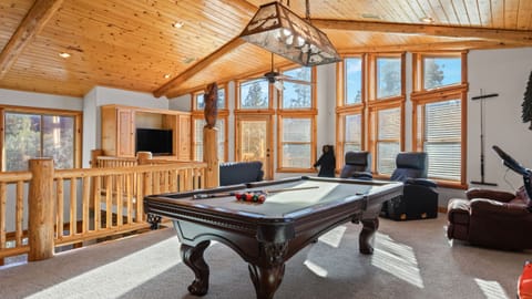 Sunlit game room with a classic pool table, lodge-style wood finishes, and relaxing lounge seating.
