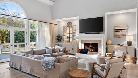 Bright and modern living room featuring a large windows, TV, comfortable sofa and a fireplace.