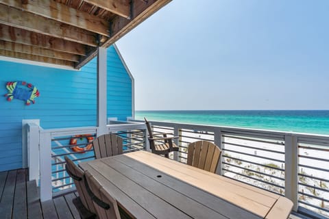 The second-level deck features a BBQ grill and an outdoor dining table.