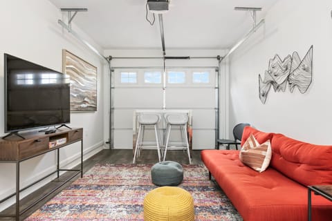 Converted garage lounge features a futon for extra sleeping space, a TV, and a table perfect for games.