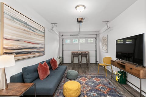 Converted garage lounge features a futon for extra sleeping space, a TV, and a table perfect for games.