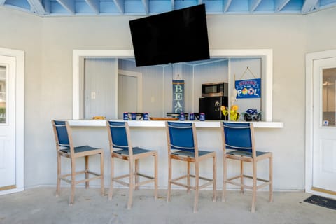 Outdoor bar area features a TV and barstool seats.