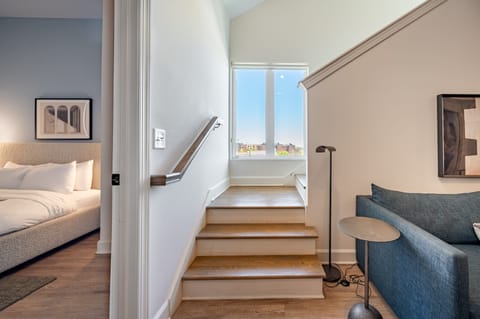 Bright stairwell area with wooden steps and a mid-century style side table and lamp.