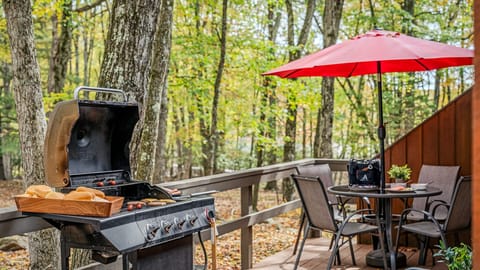 Patio area with BBQ grill, red umbrella, and forest backdrop