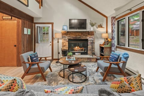 Living room with sofa, armchairs, and TV above fireplace