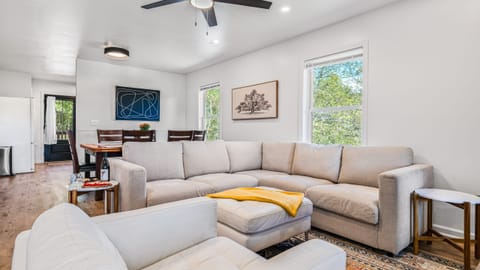 Open-concept living room with ceiling fan, sofa, and TV.