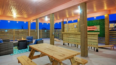 Outdoor living features a dining table, cornhole, ladder ball,  firepit table, and seating.