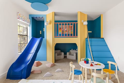 The custom-built playroom features a slide, games, and a craft table.