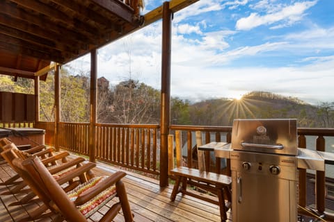 Unwind in style: balcony seating with BBQ, hot tub, and stunning mountain views at sunset.