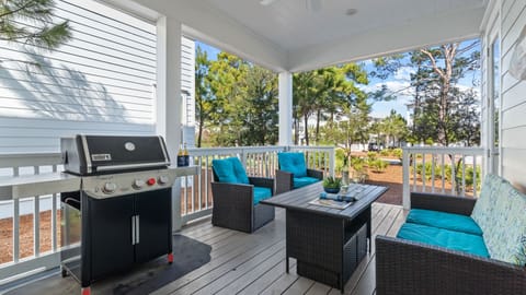 Shaded back porch with outdoor seating and a BBQ grill.