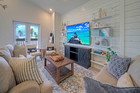 Bright and airy living room featuring cozy furnishings and a large wall-mounted TV.