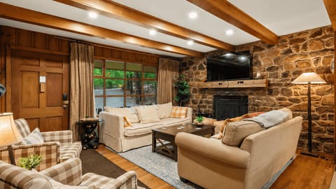 Cozy up in this warm and inviting living space with rustic wood beams, plush seating, and the perfect setup for movie nights after a day outdoors.