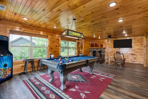 Game room featuring a pool table, arcade game, cozy seating, fireplace, and TV for endless entertainment.