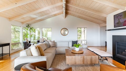 Bright and airy main living room featuring vaulted ceilings, natural light, and a fireplace.