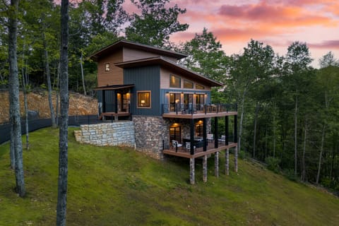 Two-story cabin with deck and forest backdrop