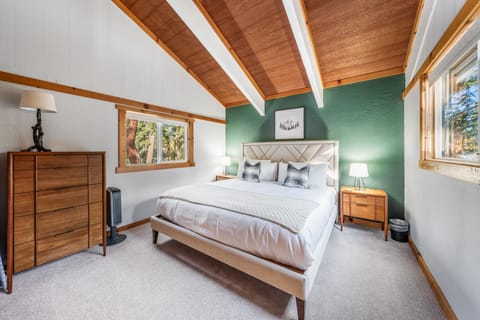 Serene bedroom under exposed beams, with soothing green accent wall.
