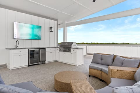 Outdoor lounge with plush seating and a large TV. (Sea Dweller)