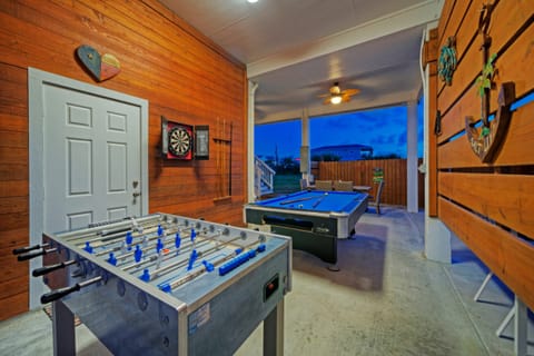 Game/covered patio area with pool table, foosball, bar table, dining table, and BBQ grill.