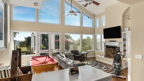 Living room with mounted TV, fireplace, & large windows.