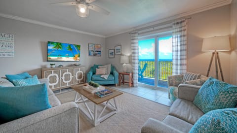 Bright coastal living room with ocean views, beach-inspired décor, and access to the balcony.