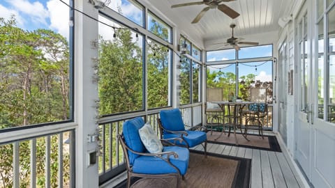 Screen-in balcony with treetop views and a ceiling fan.