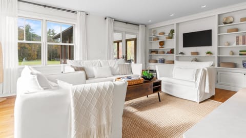 Spacious living area with white seating and built-in shelving.