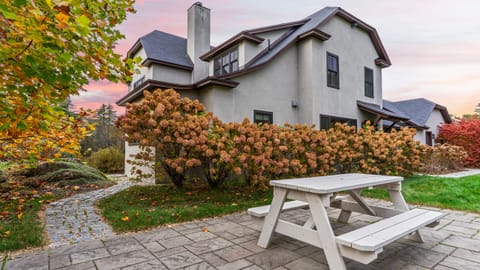 Exterior of home with stone patio and picnic table.