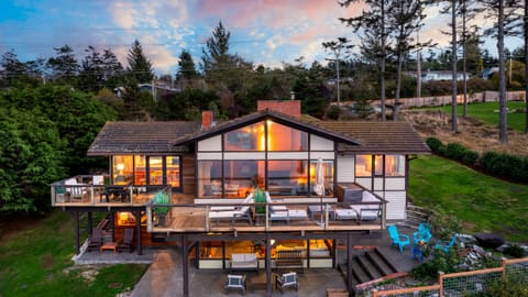 Sunset view of the main house with glowing interior lights and deck seating.