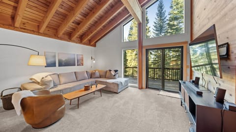 Bright open living area with vaulted wood ceilings and large windows.