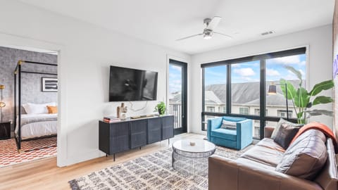 Bright living area with TV, sectional sofa, and balcony access.