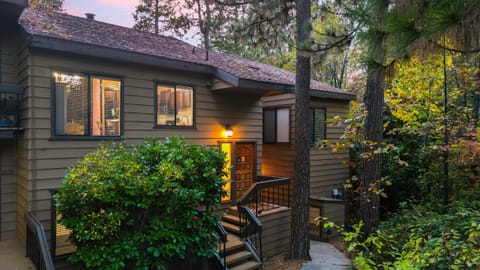 Welcoming exterior with lush greenery and warm cabin charm.