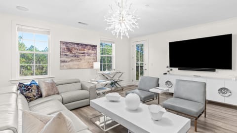 Bright, modern living room with plush seating and large windows overlooking the trees.