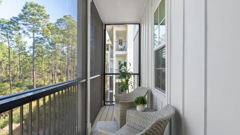 Private screened balcony with cozy seating and serene treetop views—perfect for morning coffee.