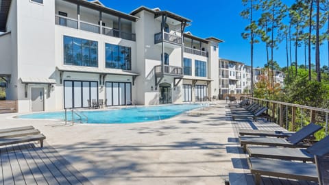 Resort-style community pool with ample lounge seating and a peaceful wooded backdrop.