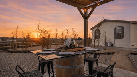 Outdoor dining table with place settings on a barrel base at dusk.