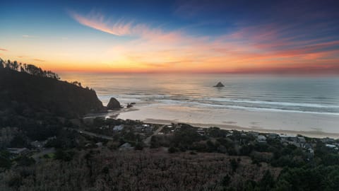 Scenic view of a dramatic sunset over the ocean and forested cliffs.