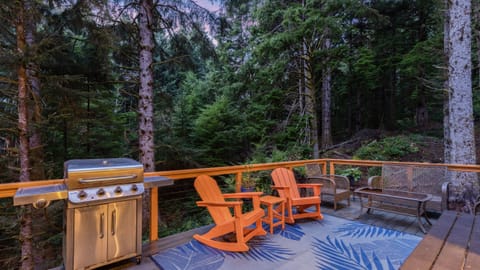 Outdoor grilling and patio area on the deck with two orange Adirondack chairs.