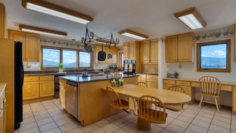 Spacious kitchen with tile flooring, light wood cabinetry, a central island, and a dining area.