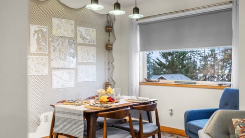 Dining area with pendant lights, a wooden table, four chairs, and a decorative wall.