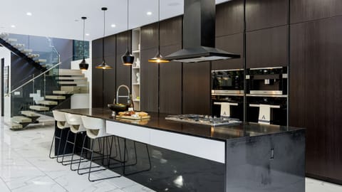 Designer chef’s kitchen with oversized waterfall island, premium appliances, and statement pendant lighting.