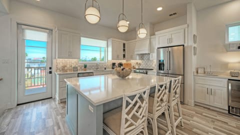 Open-concept kitchen with island, white cabinetry, and hanging pendant lights.