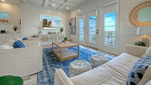 Bright living room with white sofas, a ceiling fan, and a TV.