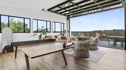 Indoor–outdoor lounge with panoramic Lake Austin views and a convertible glass wall with access to the rooftop deck.