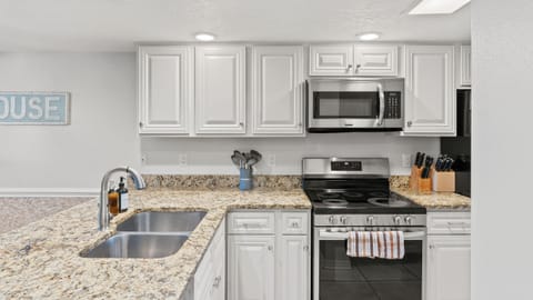 Modern kitchen featuring white cabinetry, granite countertops, and stainless steel appliances.
