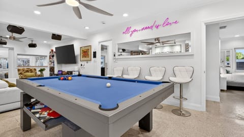 Bright game area with pool table/ping pong table and bar seating.