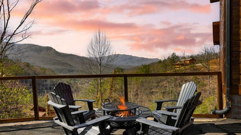 Adirondack chairs surrounding a fire pit on the deck with mountain views.