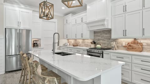 Chef’s kitchen featuring white cabinetry, a large island, and subway tile backsplash.
